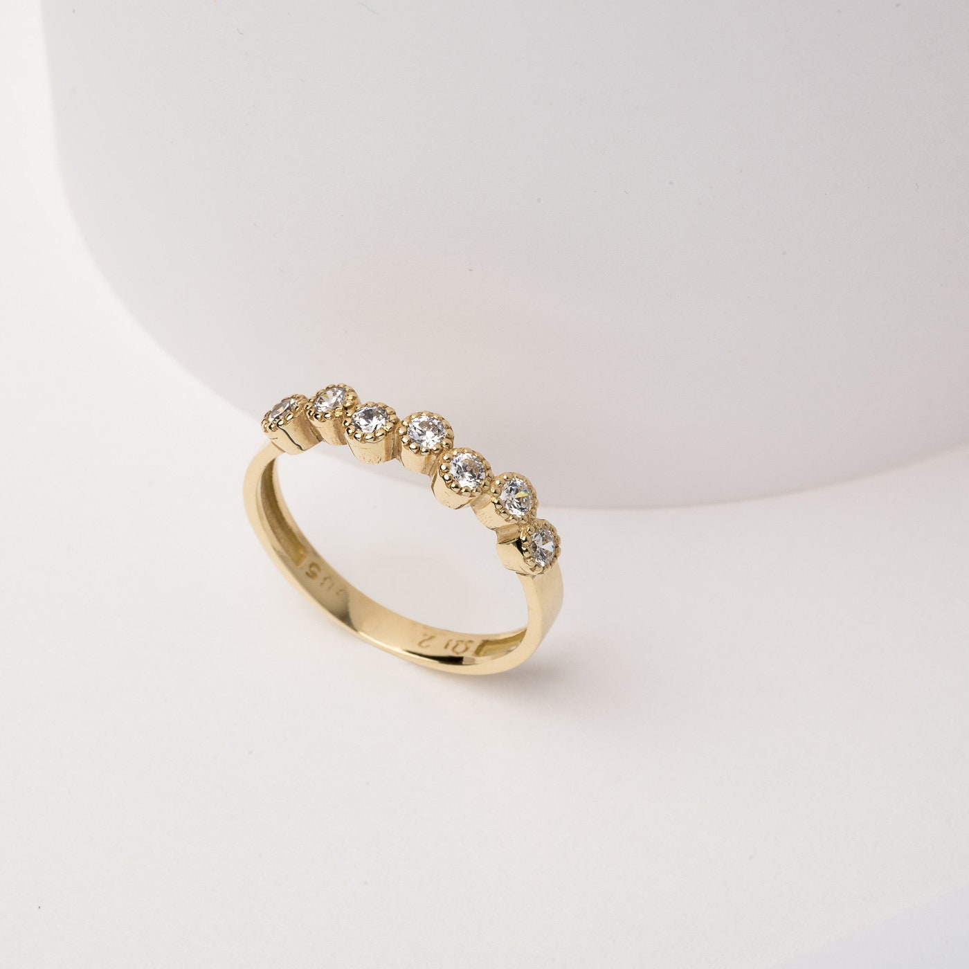 A half-eternity asymmetrical band crafted in 14k solid gold, adorned with white cubic zirconia stones.