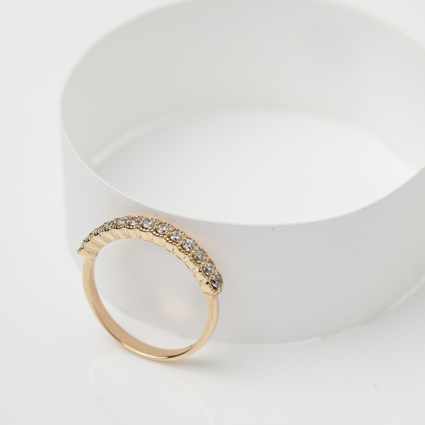 A women's half-eternity band ring featuring white cubic zirconia stones set in 14k gold.