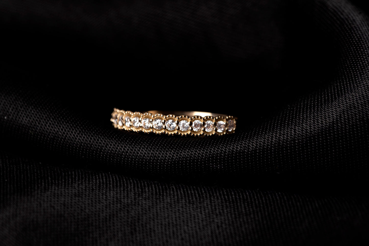 A women's half-eternity band ring featuring white cubic zirconia stones set in 14k gold.