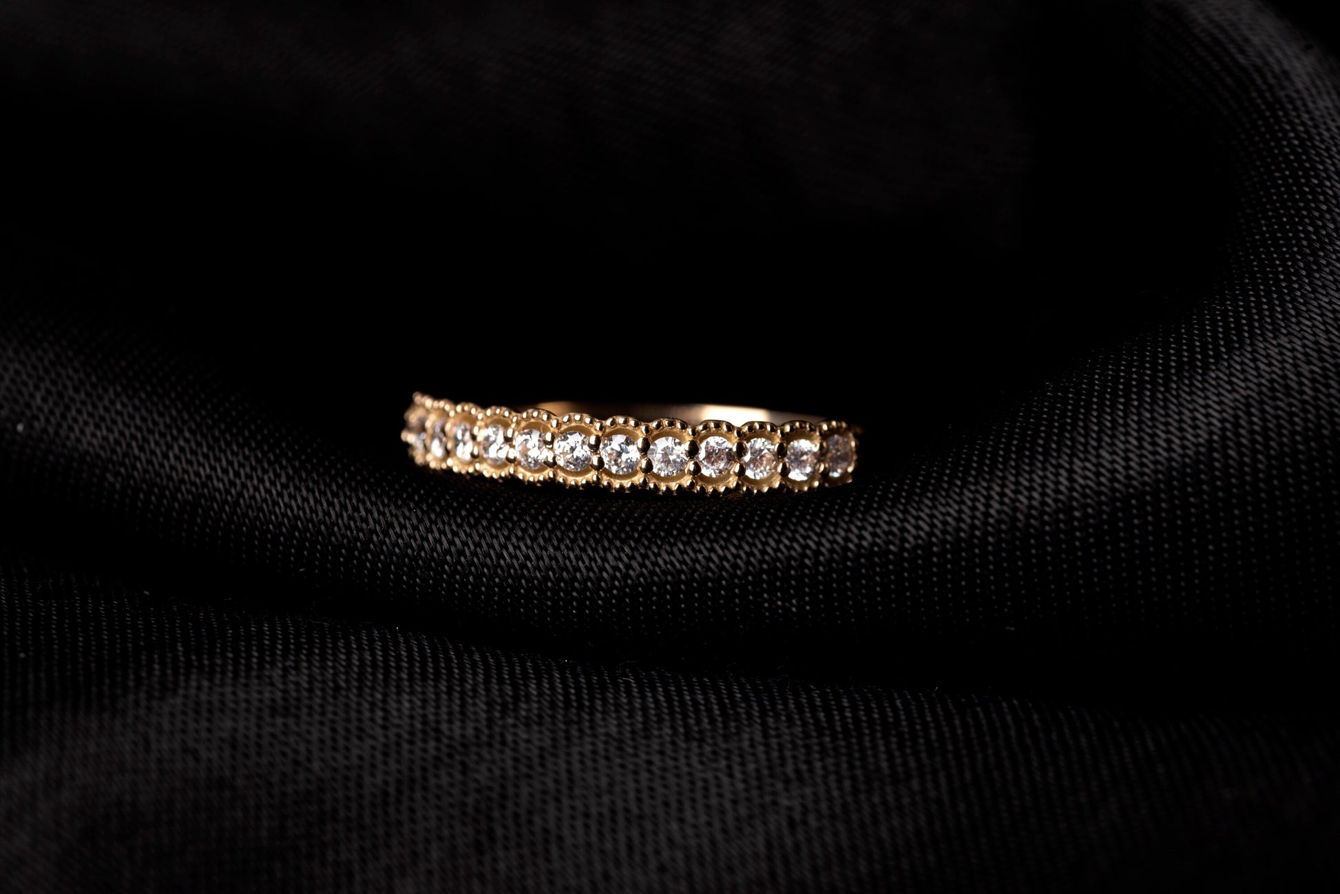 A women's half-eternity band ring featuring white cubic zirconia stones set in 14k gold.