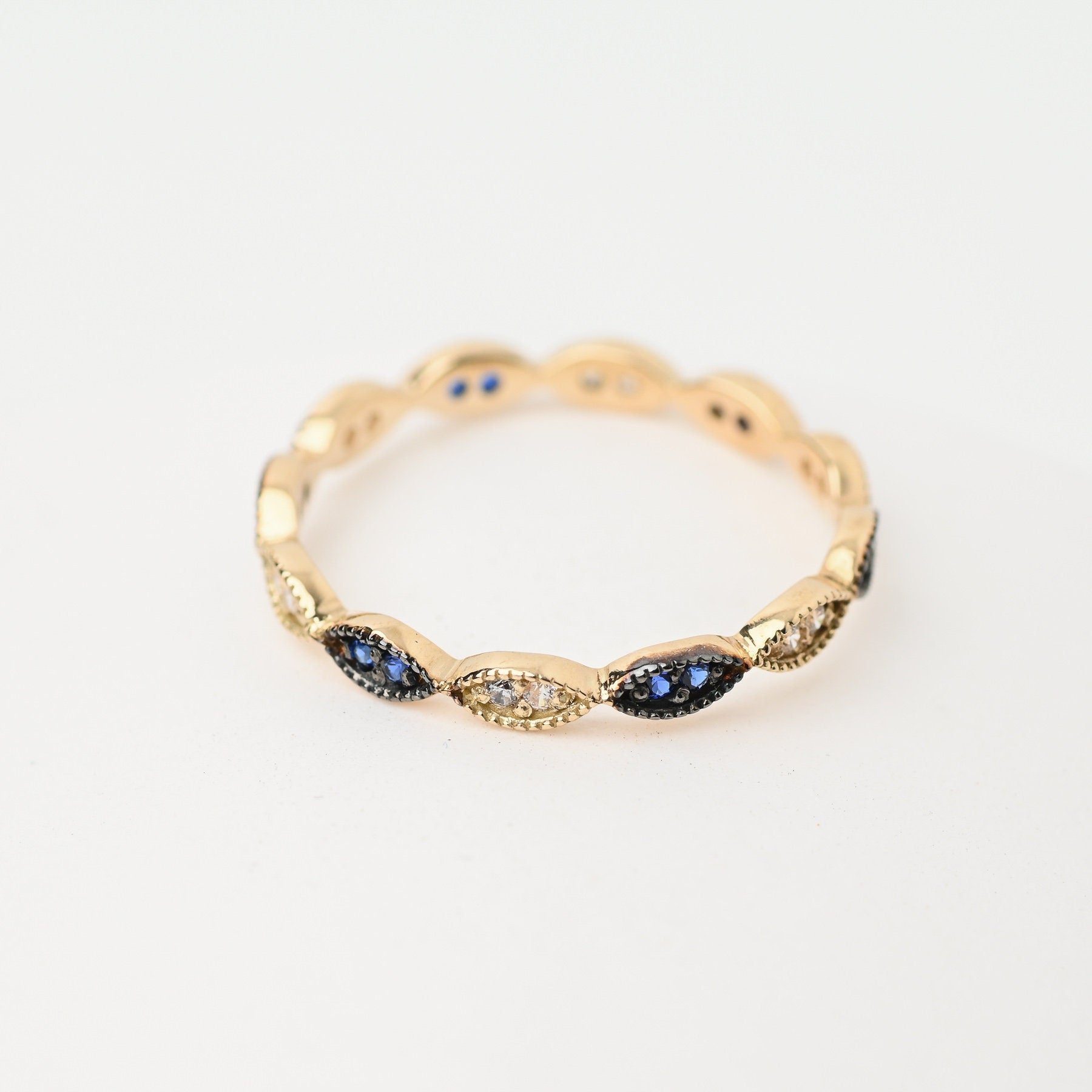 A full eternity band ring crafted in 14k gold, adorned with white and blue cubic zirconia stones.