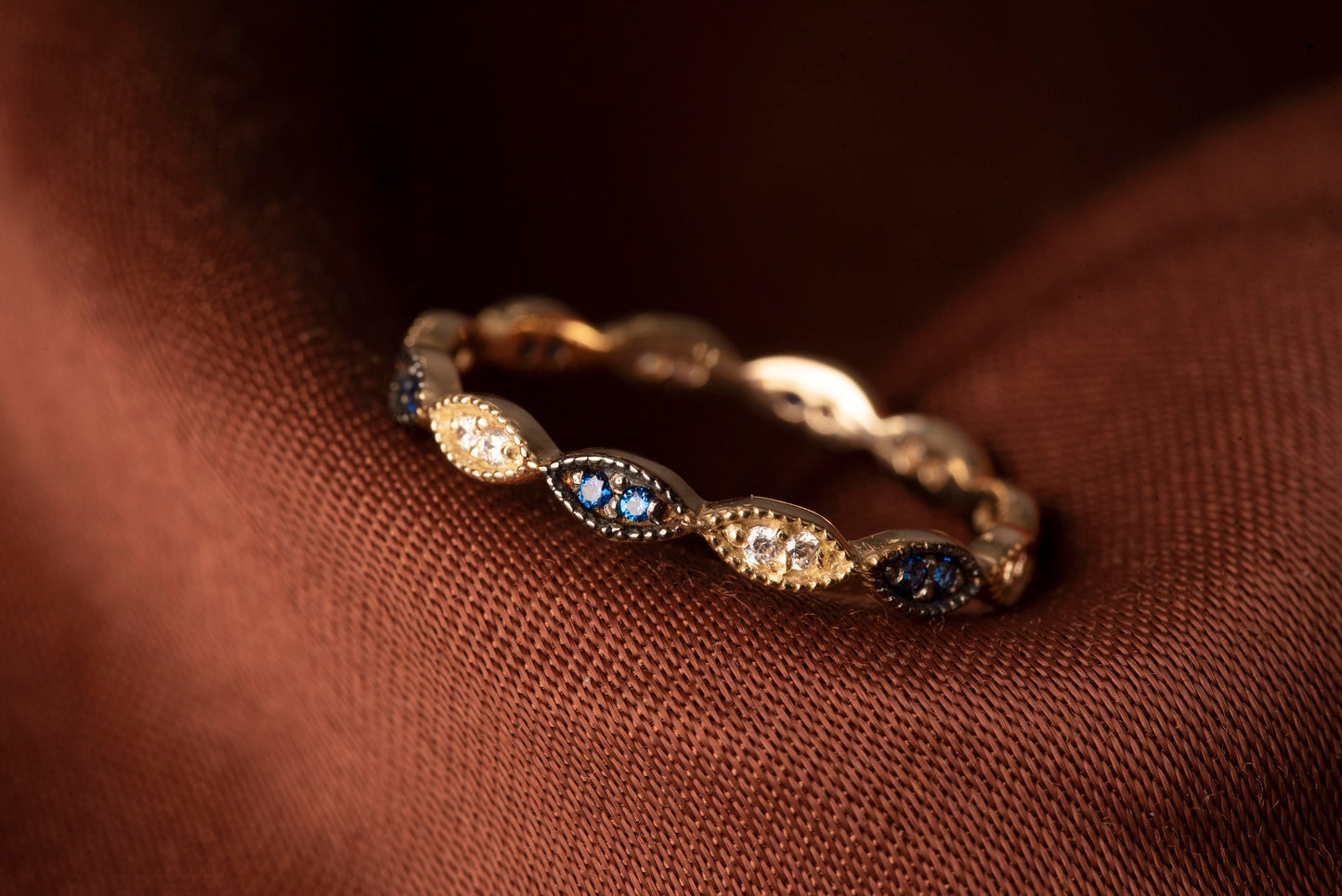 A full eternity band ring crafted in 14k gold, adorned with white and blue cubic zirconia stones.