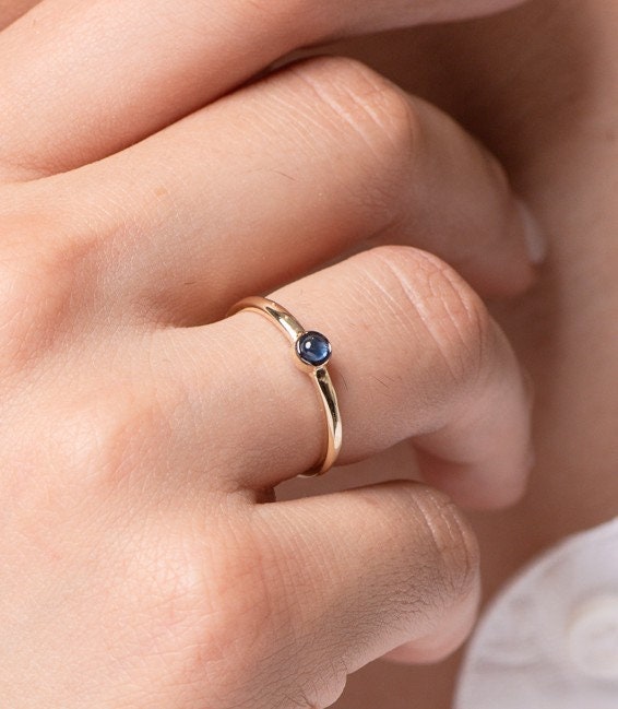 A handmade ring featuring a single birthstone in a bezel setting, crafted in 14k gold for women.