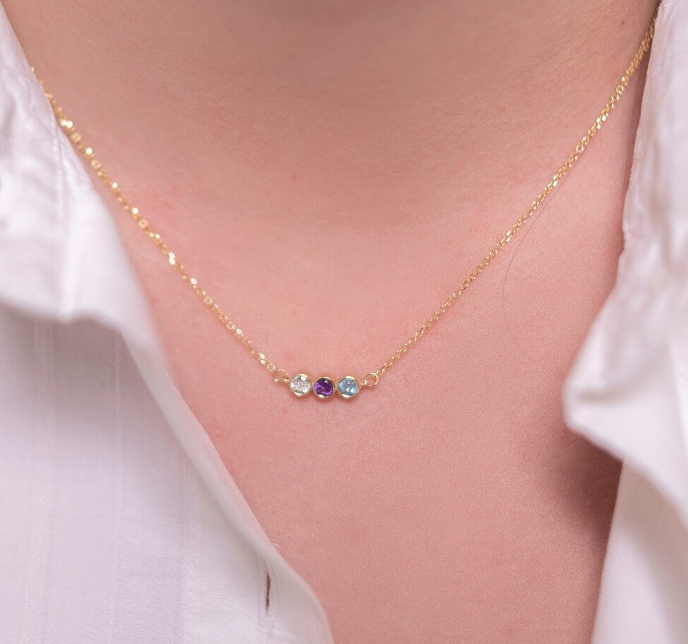 A 14k gold birthstone necklace for women, featuring three stones in a bezel setting.