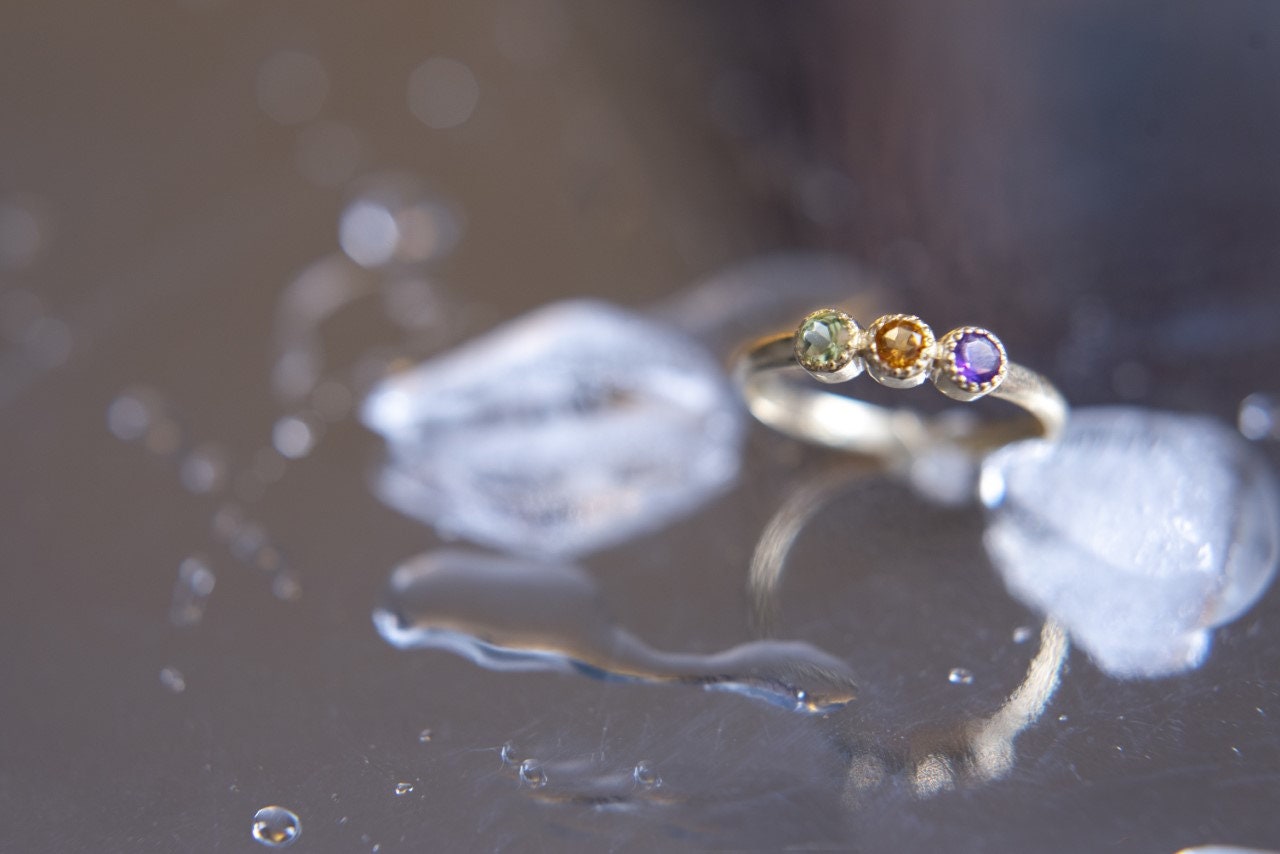 A handmade ring featuring three birthstones set in 14k solid gold with a prong setting.