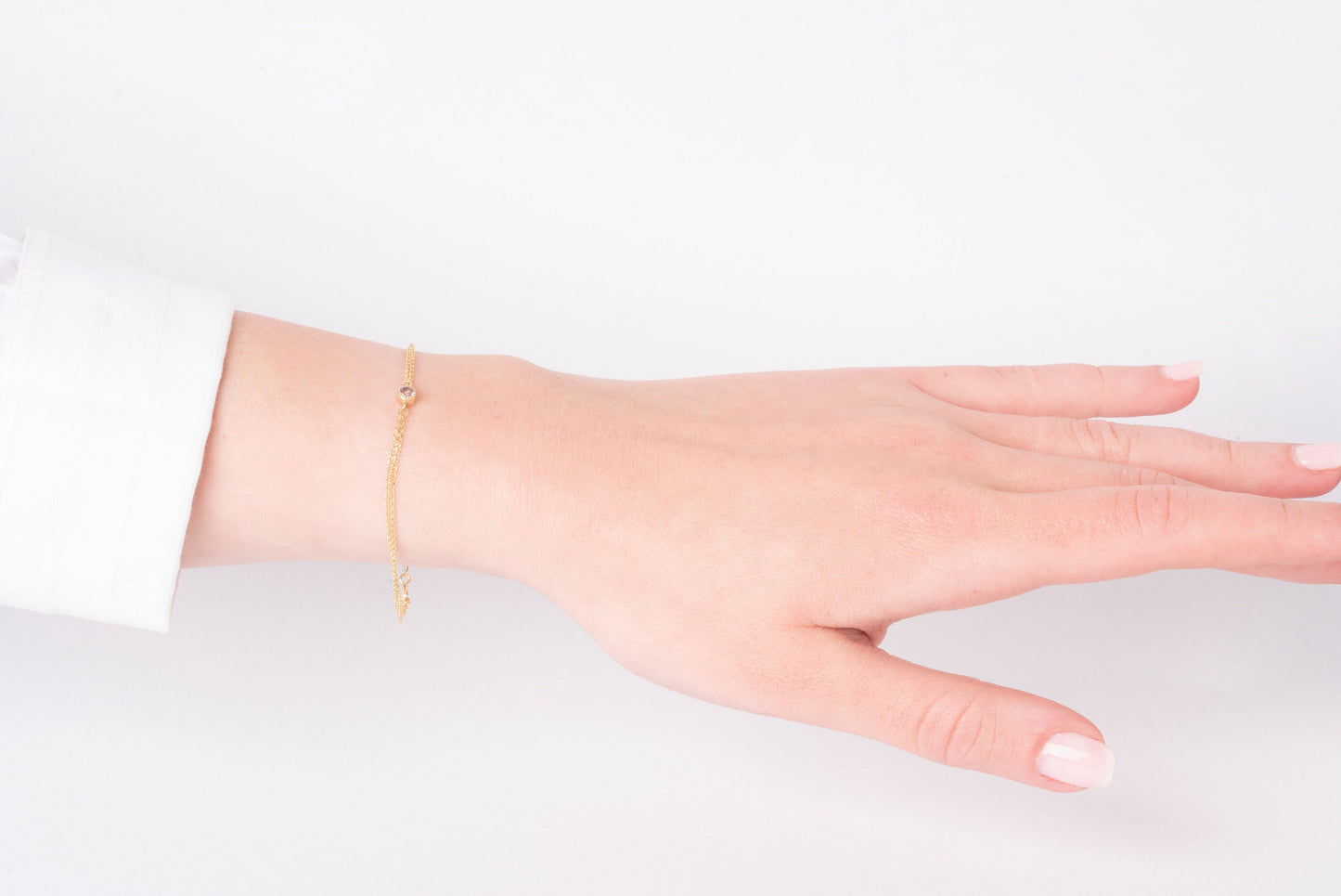 A handmade bracelet featuring a single birthstone set in 14k gold, complemented by a double chain design.