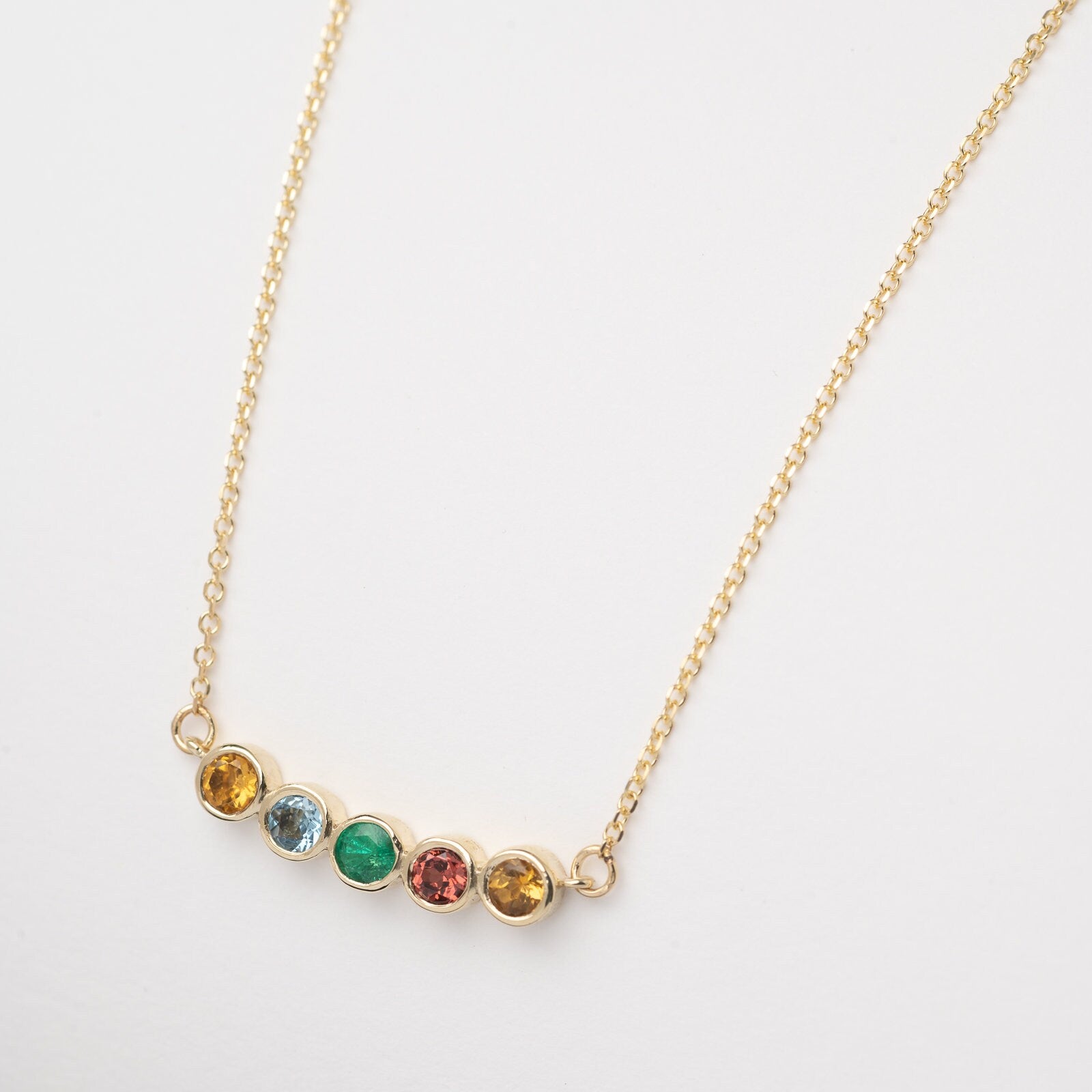 A 14k gold necklace for women, featuring five family birthstones.