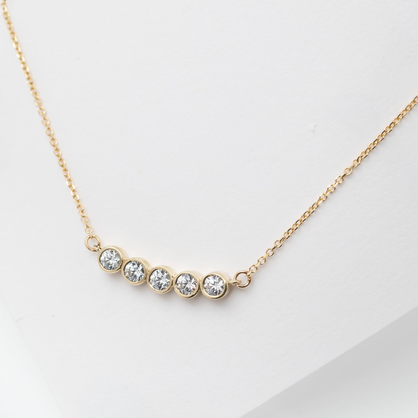 A 14k gold necklace for women, featuring five family birthstones.