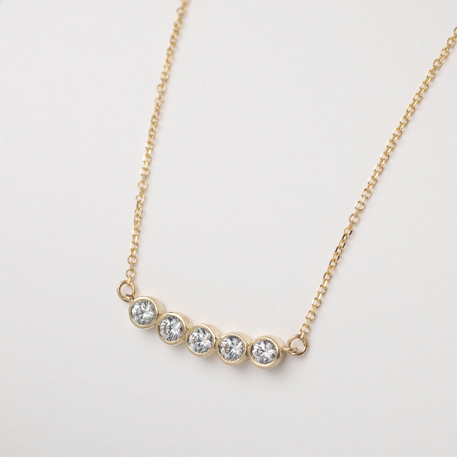 A 14k gold necklace for women, featuring five family birthstones.