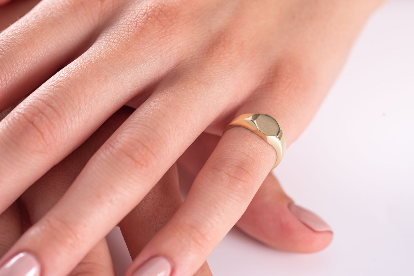 A model wears a minimalist personalized signet ring crafted in 14K gold on their pinky finger.