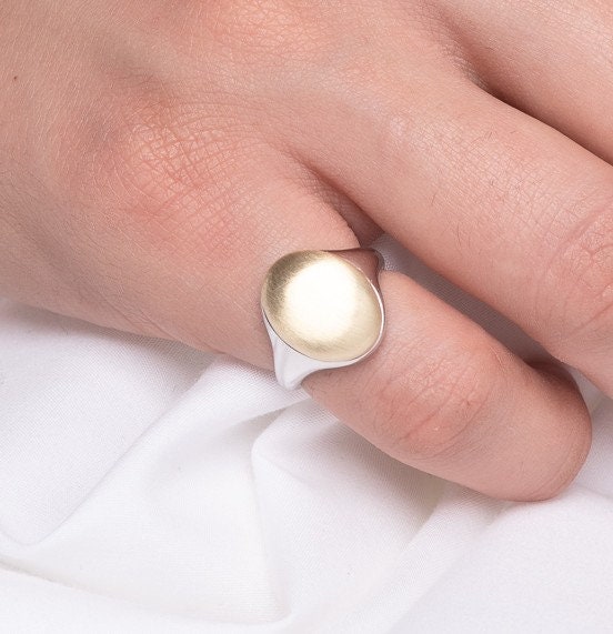 An oval personalized signet ring for women in 14k gold, with the top part engravable.